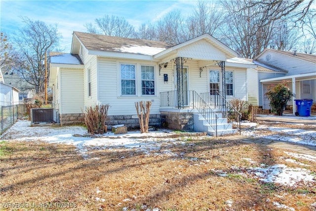 bungalow-style home with central air condition unit and fence