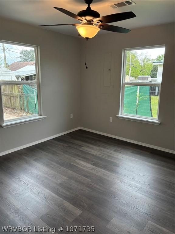 unfurnished room featuring plenty of natural light, dark hardwood / wood-style floors, and ceiling fan