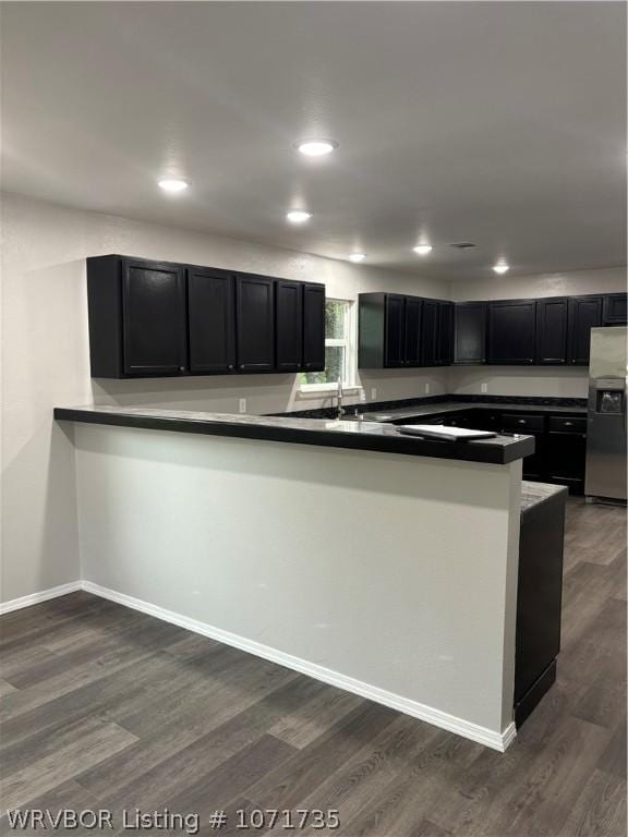 kitchen featuring kitchen peninsula, stainless steel fridge with ice dispenser, and dark wood-type flooring