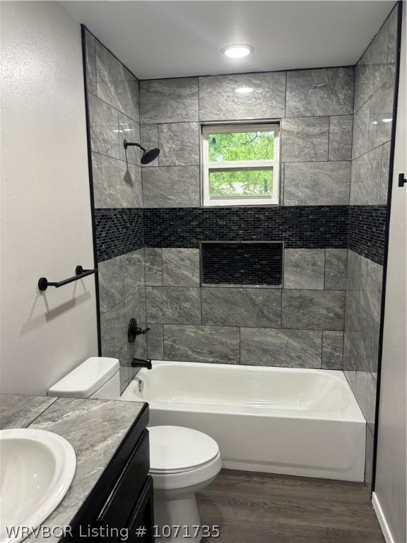 full bathroom featuring hardwood / wood-style flooring, vanity, toilet, and tiled shower / bath