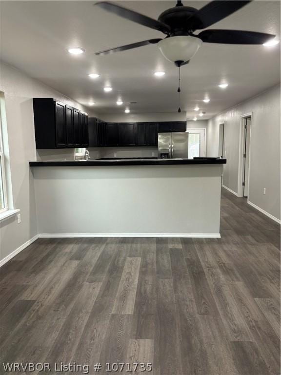 kitchen with kitchen peninsula, dark hardwood / wood-style floors, stainless steel refrigerator, and ceiling fan