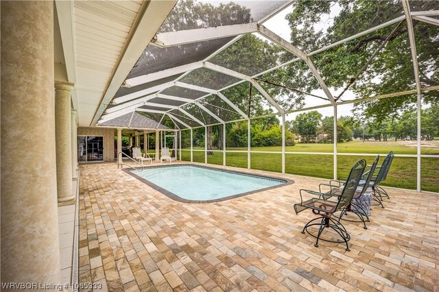 view of pool featuring a patio, glass enclosure, and a lawn