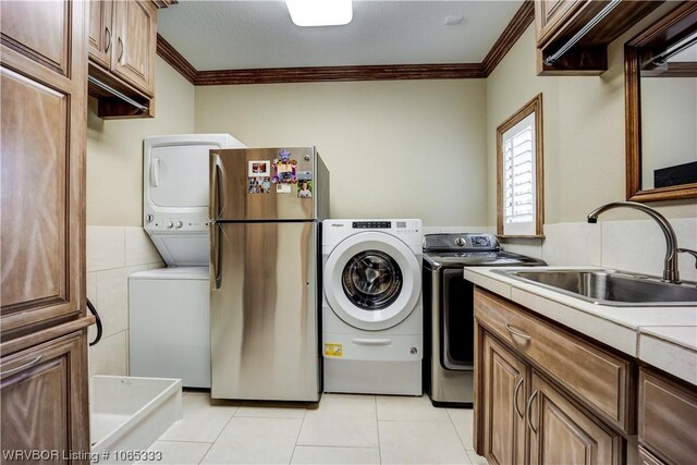 clothes washing area featuring ornamental molding, sink, light tile patterned floors, and tile walls