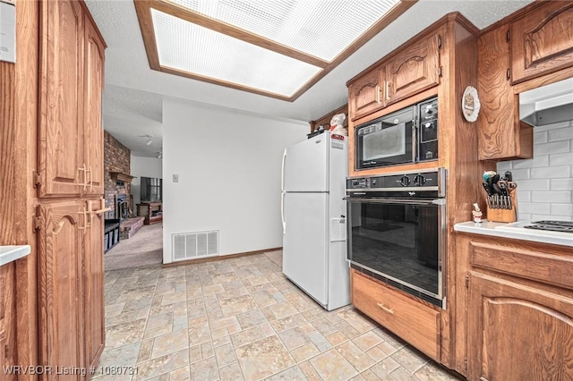 3009 Shadow Lake Dr, Greenwood, AR 72936 - kitchen with brown cabinets, a brick fireplace, stone finish floor, visible vents, and black appliances