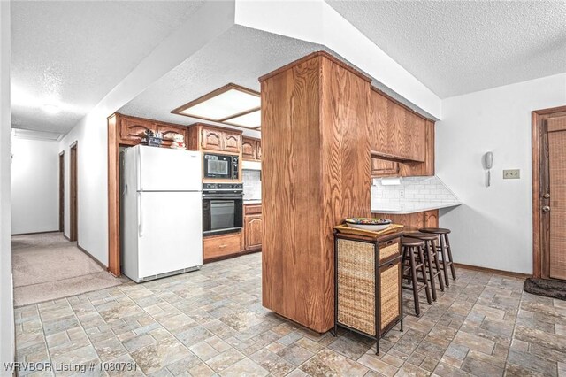 3009 Shadow Lake Dr, Greenwood, AR 72936 - kitchen featuring brown cabinets, a textured ceiling, black appliances, and stone tile flooring
