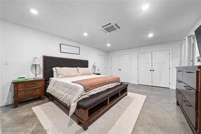 bedroom with multiple closets and concrete flooring