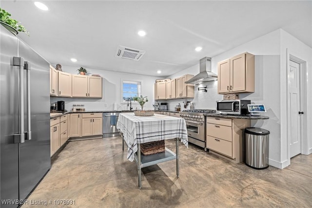 kitchen featuring premium appliances, wall chimney exhaust hood, and light brown cabinets