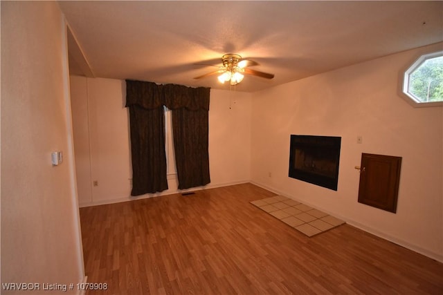 unfurnished living room featuring a ceiling fan, a fireplace, and wood finished floors