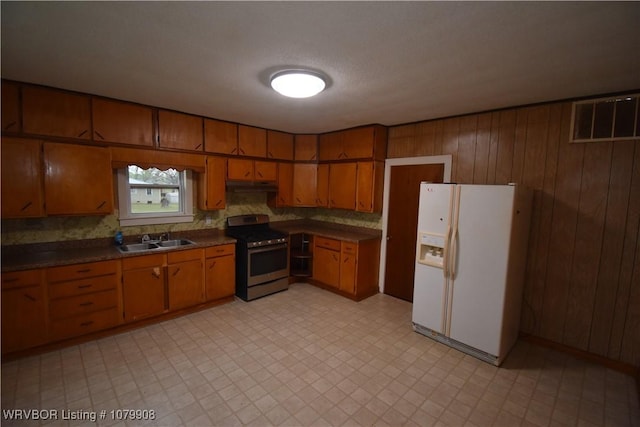 kitchen with a sink, white refrigerator with ice dispenser, brown cabinets, visible vents, and stainless steel electric stove