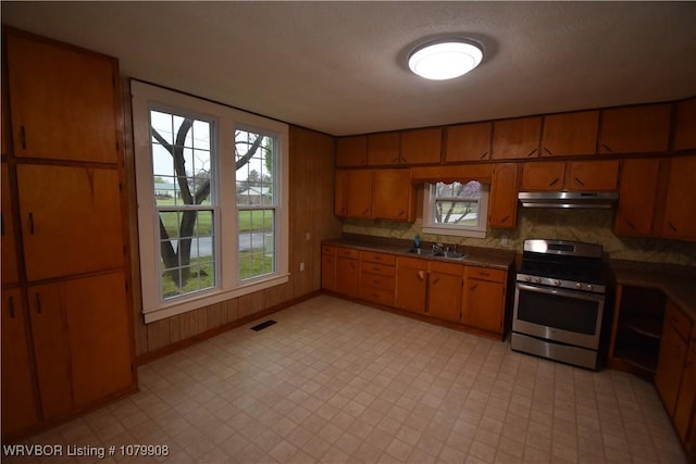 kitchen featuring gas stove, under cabinet range hood, visible vents, and light floors