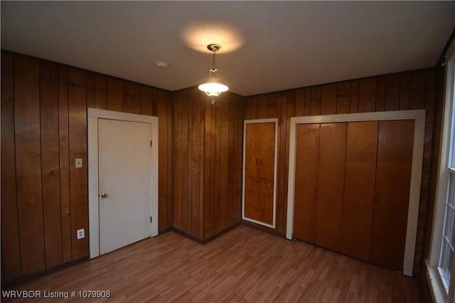 unfurnished bedroom with wood finished floors and wood walls