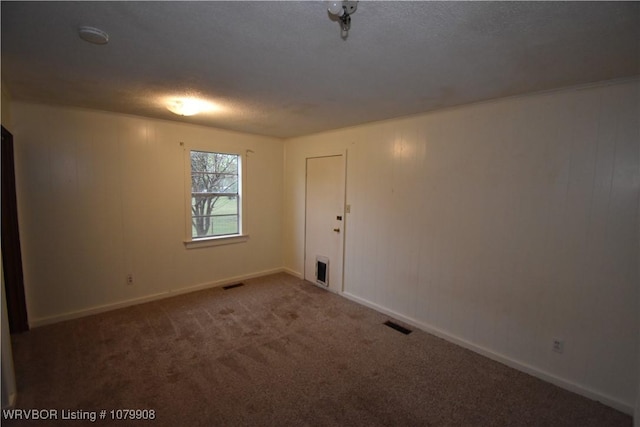 carpeted spare room with baseboards, a textured ceiling, and visible vents