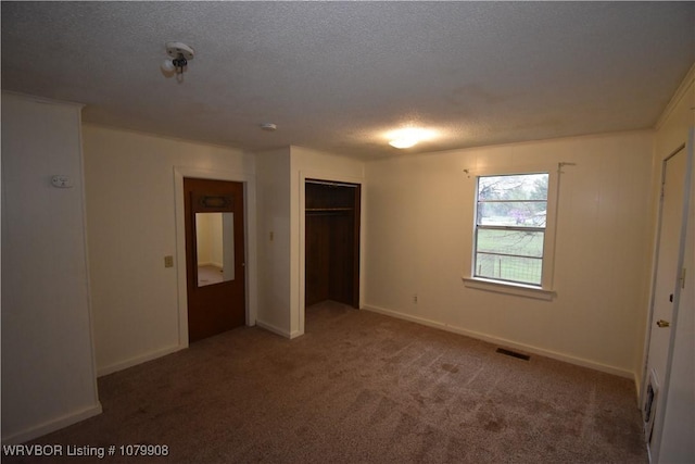 unfurnished bedroom featuring a closet, carpet floors, a textured ceiling, baseboards, and visible vents
