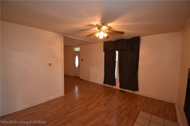unfurnished room with baseboards, visible vents, wood finished floors, and ceiling fan
