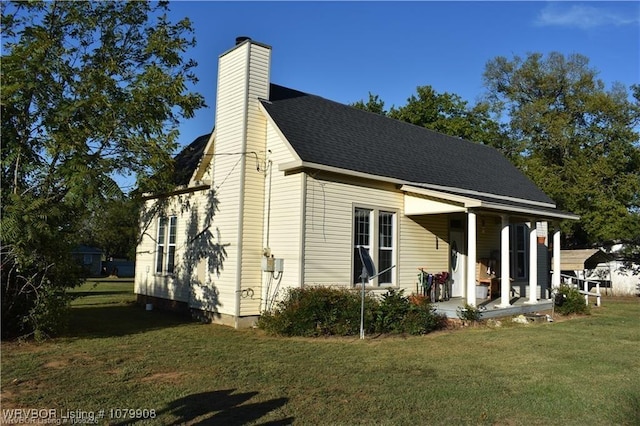 view of home's exterior with a lawn, a shingled roof, a chimney, and a porch
