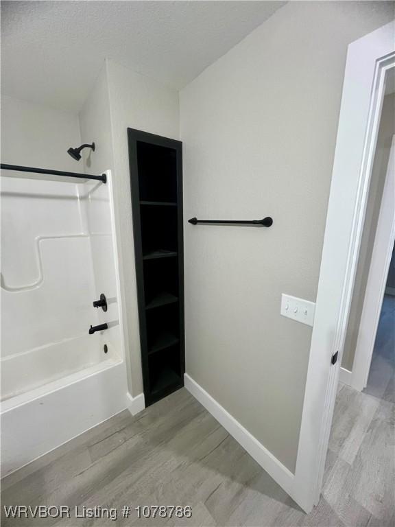 bathroom with shower / washtub combination and hardwood / wood-style floors