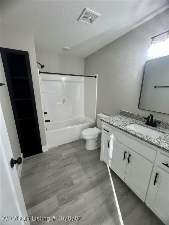 full bath with  shower combination, wood finished floors, toilet, and visible vents