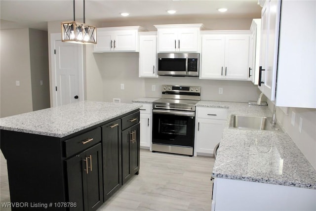 kitchen featuring pendant lighting, sink, appliances with stainless steel finishes, white cabinetry, and a kitchen island