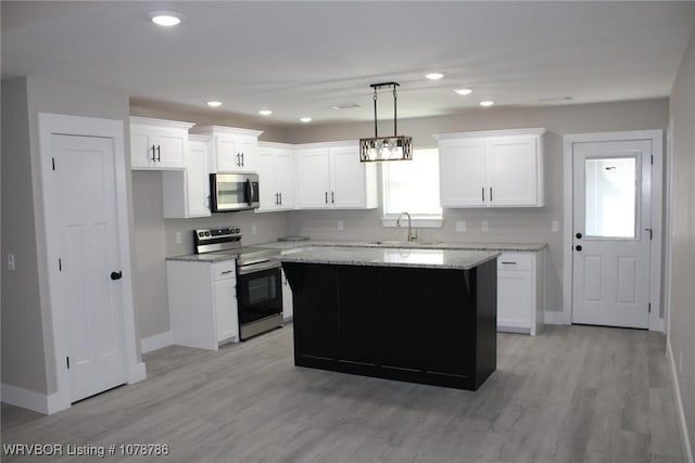 kitchen with light stone counters, appliances with stainless steel finishes, a kitchen island, pendant lighting, and white cabinets