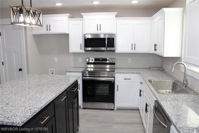 kitchen featuring white cabinets, a sink, dark cabinetry, and appliances with stainless steel finishes