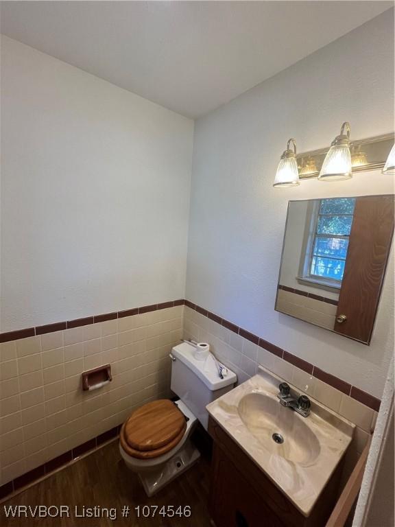 bathroom with vanity, toilet, and tile walls