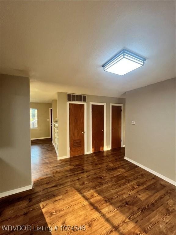 unfurnished room with dark wood-type flooring