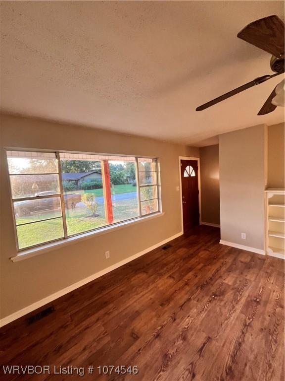 interior space with a textured ceiling, dark hardwood / wood-style floors, a wealth of natural light, and ceiling fan