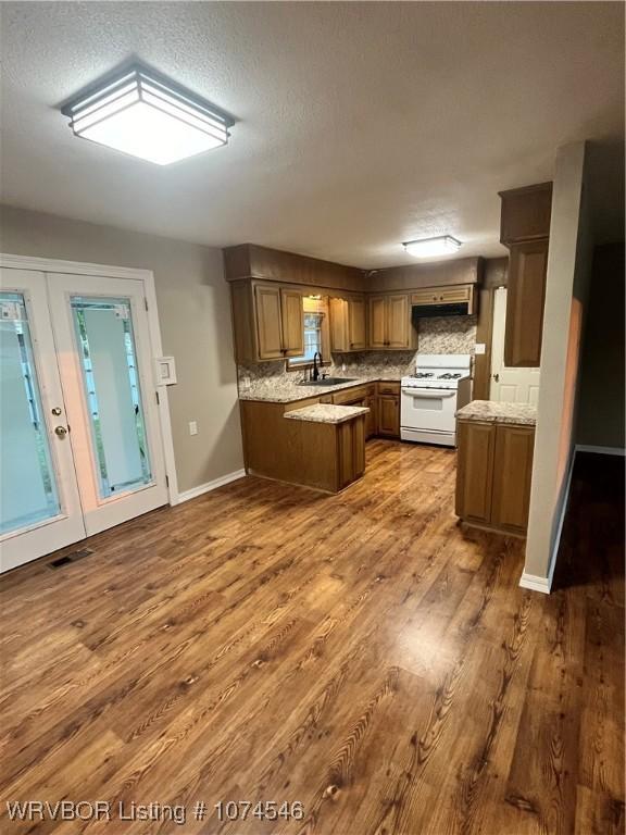 kitchen featuring white range, sink, kitchen peninsula, tasteful backsplash, and wood-type flooring