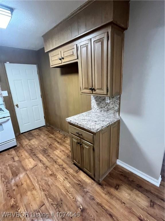 kitchen featuring light stone countertops, white electric range, backsplash, and hardwood / wood-style floors