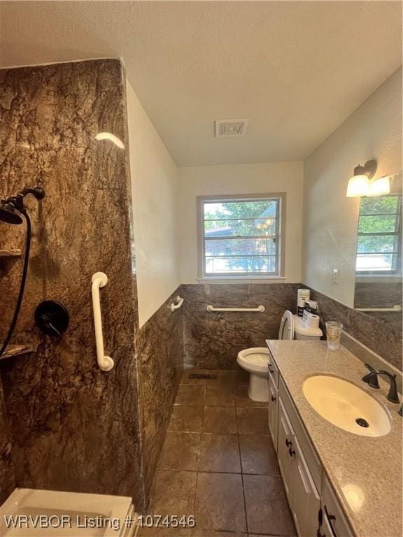 bathroom featuring tile patterned floors, vanity, tile walls, and toilet