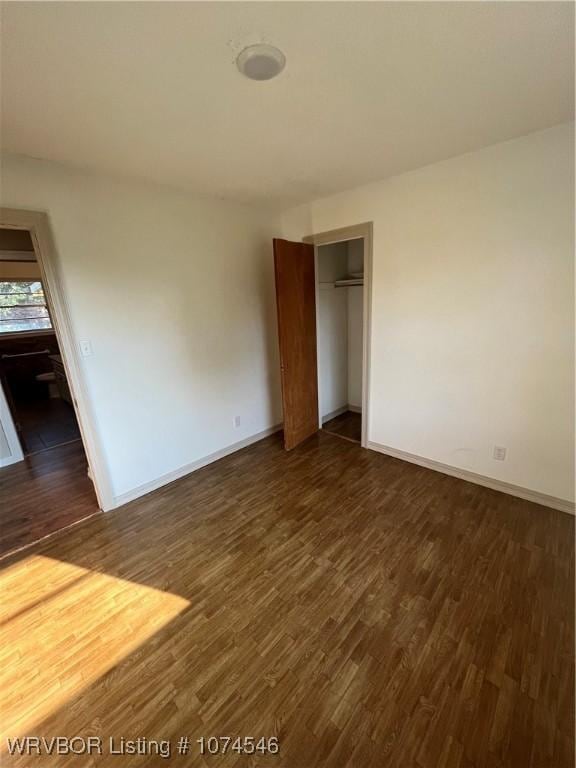 unfurnished bedroom featuring a closet and dark wood-type flooring