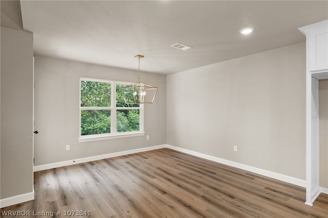 spare room with hardwood / wood-style floors and a chandelier