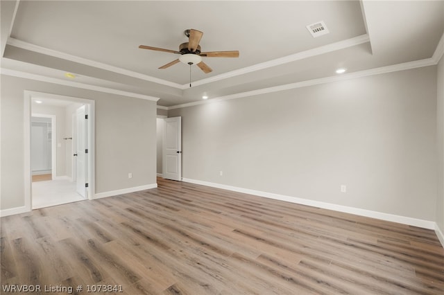 spare room featuring ceiling fan, a raised ceiling, crown molding, and light hardwood / wood-style flooring