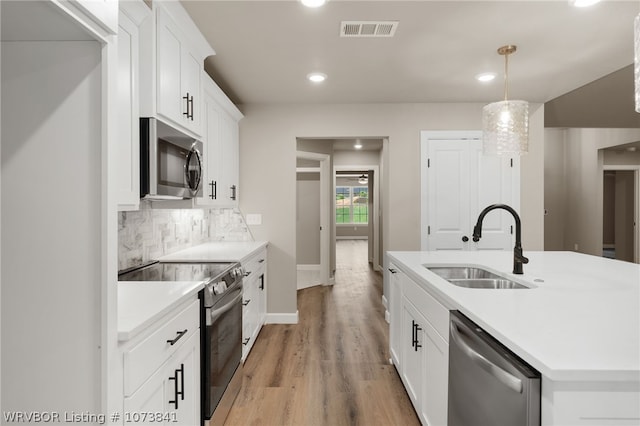 kitchen with white cabinets, sink, hanging light fixtures, tasteful backsplash, and stainless steel appliances