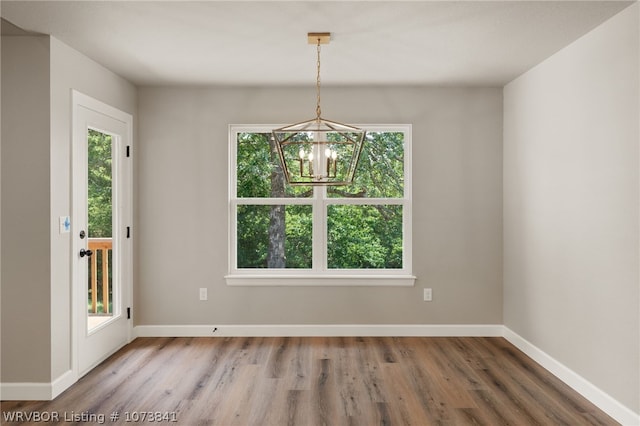 unfurnished dining area with wood-type flooring and a notable chandelier