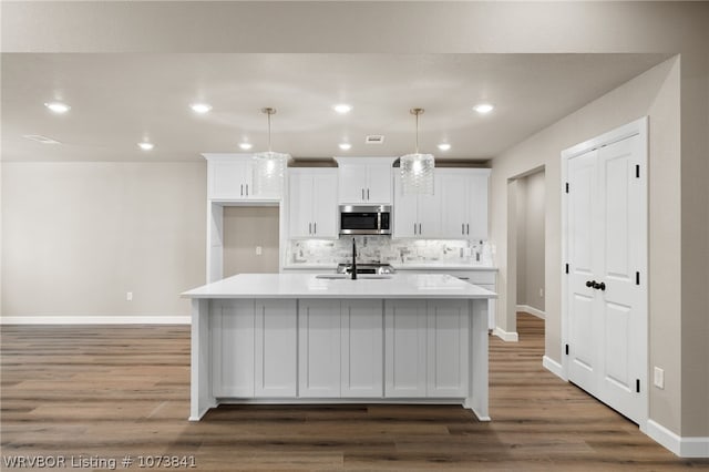 kitchen featuring a center island with sink, dark hardwood / wood-style floors, white cabinets, and backsplash