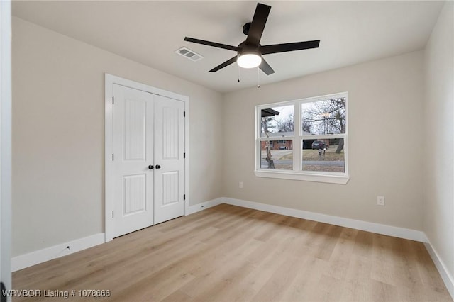 unfurnished bedroom featuring ceiling fan, a closet, and light wood-type flooring