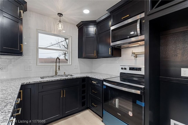 kitchen featuring appliances with stainless steel finishes, decorative light fixtures, tasteful backsplash, sink, and light stone counters