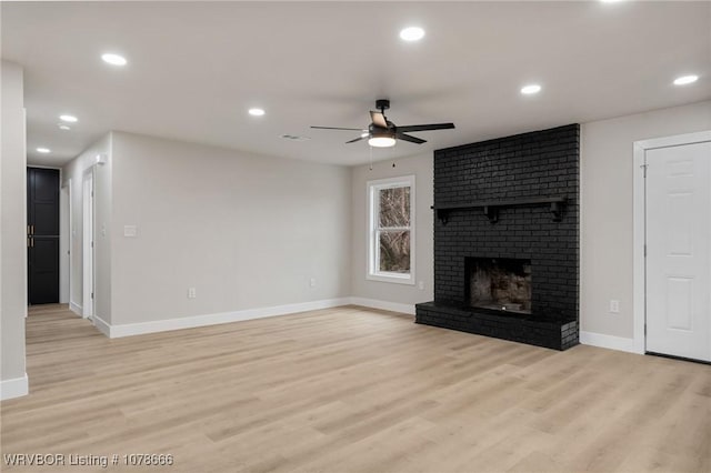 unfurnished living room with ceiling fan, a fireplace, and light hardwood / wood-style floors