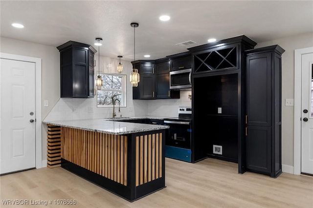 kitchen featuring light wood-type flooring, kitchen peninsula, pendant lighting, stainless steel appliances, and light stone countertops