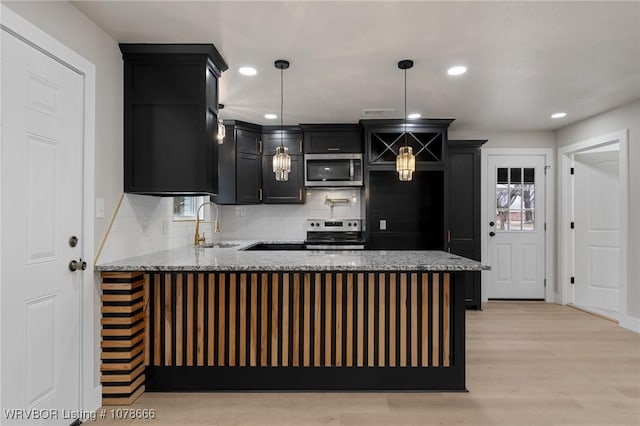 kitchen featuring sink, tasteful backsplash, light hardwood / wood-style flooring, appliances with stainless steel finishes, and pendant lighting