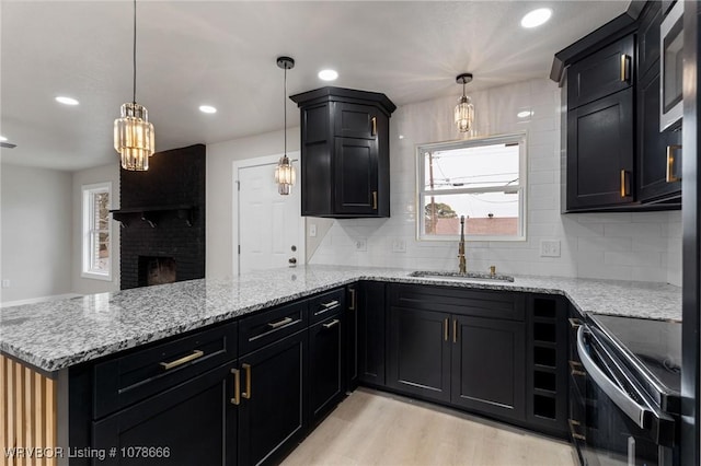 kitchen featuring black / electric stove, sink, kitchen peninsula, and decorative light fixtures