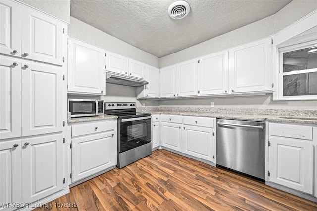 kitchen with light stone counters, a textured ceiling, stainless steel appliances, dark wood-type flooring, and white cabinetry