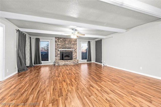 unfurnished living room with beam ceiling, ceiling fan, a textured ceiling, and hardwood / wood-style flooring