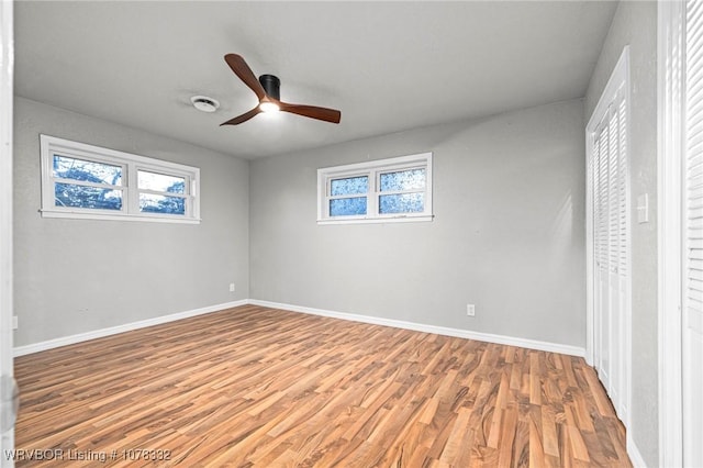 unfurnished bedroom with hardwood / wood-style flooring, ceiling fan, and multiple windows