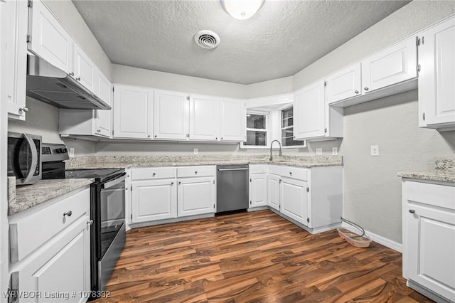 kitchen with light stone counters, white cabinetry, stainless steel appliances, and dark wood-type flooring