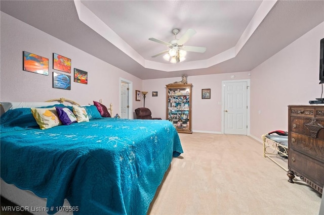 bedroom with carpet flooring, a raised ceiling, and ceiling fan