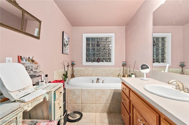 bathroom with tile patterned floors, vanity, and a relaxing tiled tub