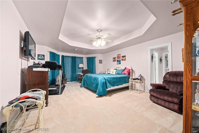 carpeted bedroom featuring ceiling fan and a tray ceiling