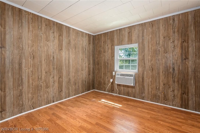 unfurnished room featuring hardwood / wood-style flooring, crown molding, wooden walls, and a wall mounted AC